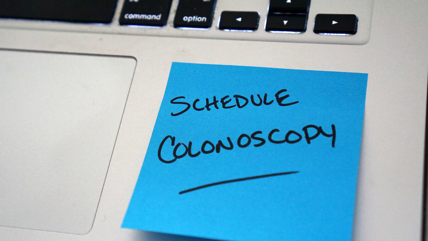 Sticky note on computer that says schedule colonoscopy