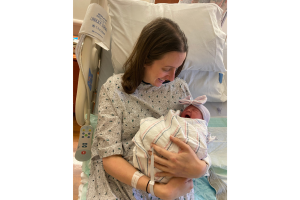 Carla Karp smiling while cradling her infant daughter after experiencing intrahepatic cholestasis of pregnancy (ICP)